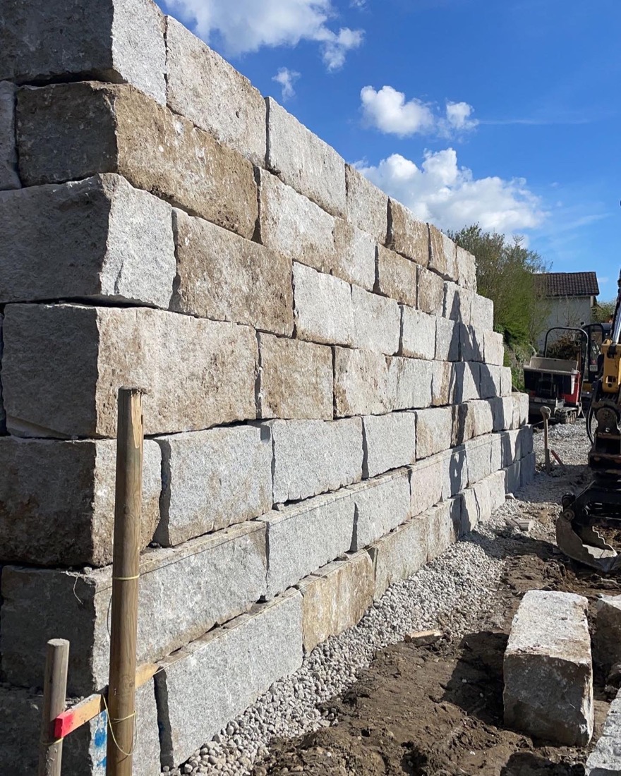 Bau einer Natursteinmauer mit Bagger